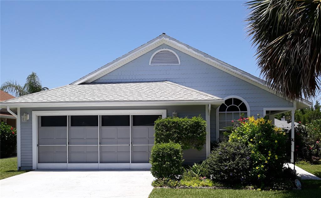 A light blue house with a two-car garage and a front yard under a clear sky — 25 ANDOVER DRIVE, PALM COAST, FL