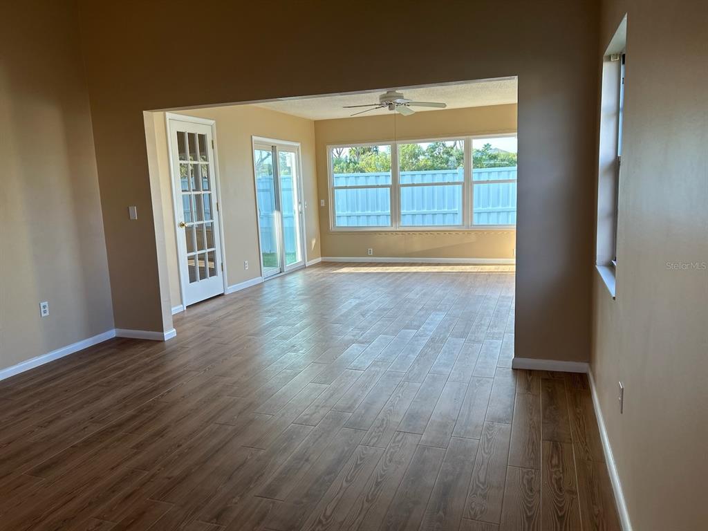 A living room with wood-look flooring, a ceiling fan, and a glass door to outside — 25 ANDOVER DRIVE, PALM COAST, FL