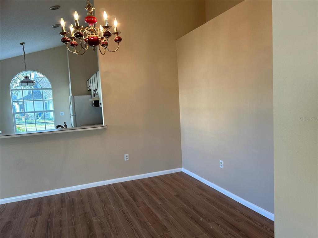 A dining area with wood-look flooring, a chandelier, and a pass-through window to the kitchen — 25 ANDOVER DRIVE, PALM COAST, FL
