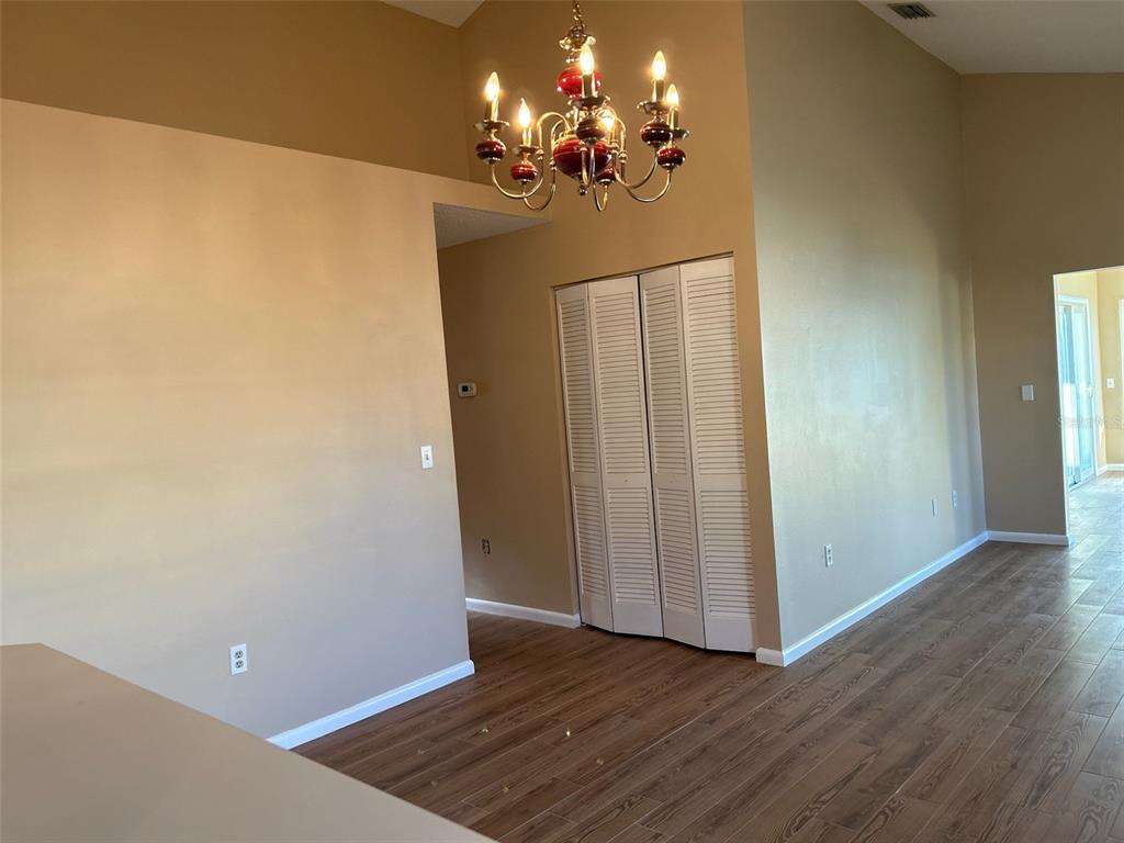 A room with wood-look flooring, beige walls, a chandelier, and white louvered closet doors — 25 ANDOVER DRIVE, PALM COAST, FL