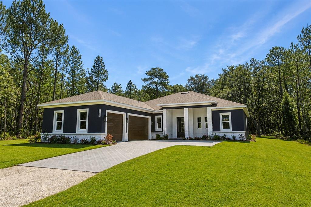 A modern single-story house with dark siding, white stone accents, and a paved driveway — 16098 MELLON ROAD, WEEKI WACHEE, FL