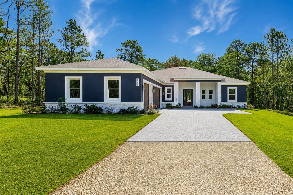 A single-story house with dark blue siding, white trim, and a paved driveway — 16098 MELLON ROAD, WEEKI WACHEE, FL