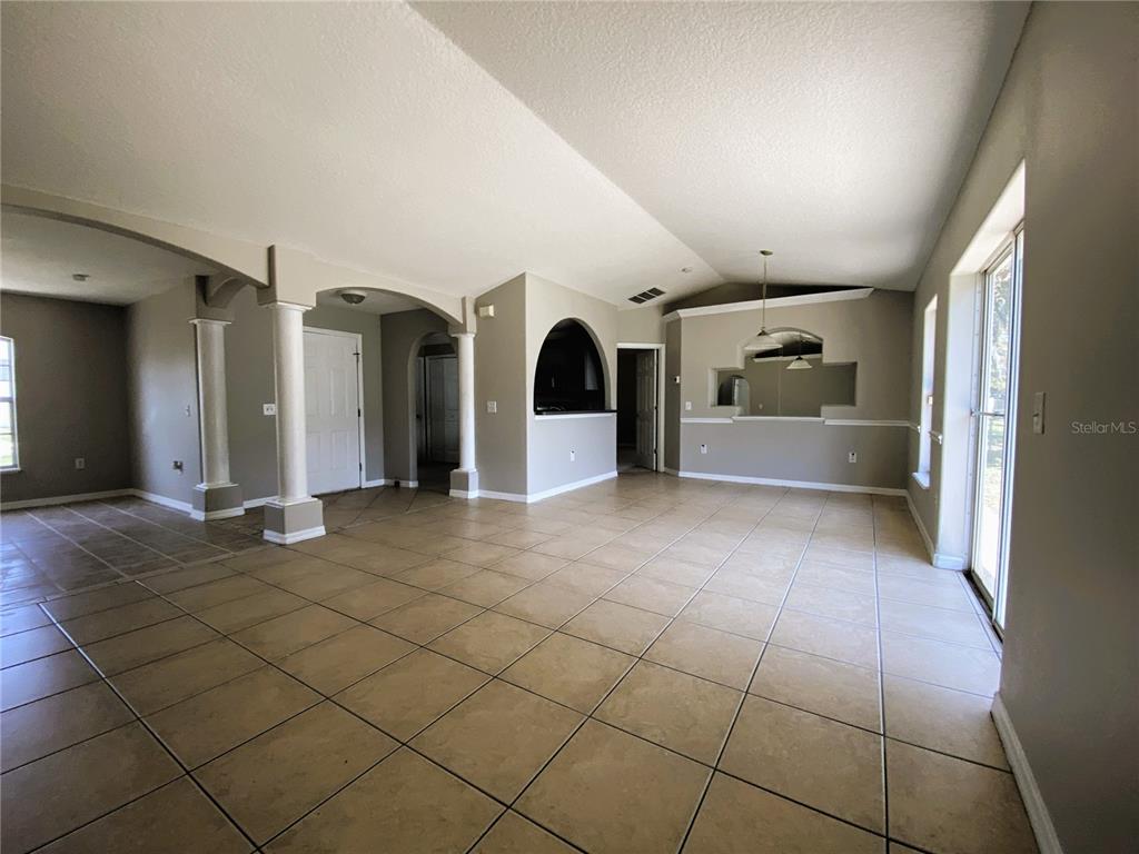 An open living area features beige tile flooring, arched entryways, decorative columns, and neutral walls — 311 BACCARAT COURT, KISSIMMEE, FL