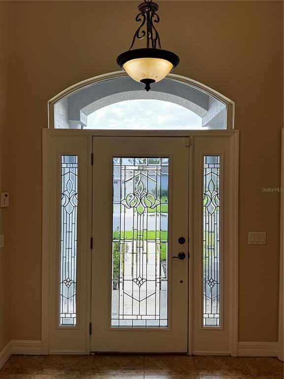 A white front door with decorative glass panels sits beneath an arched transom window — 6871 EAGLE RIDGE LOOP, LAKELAND, FL
