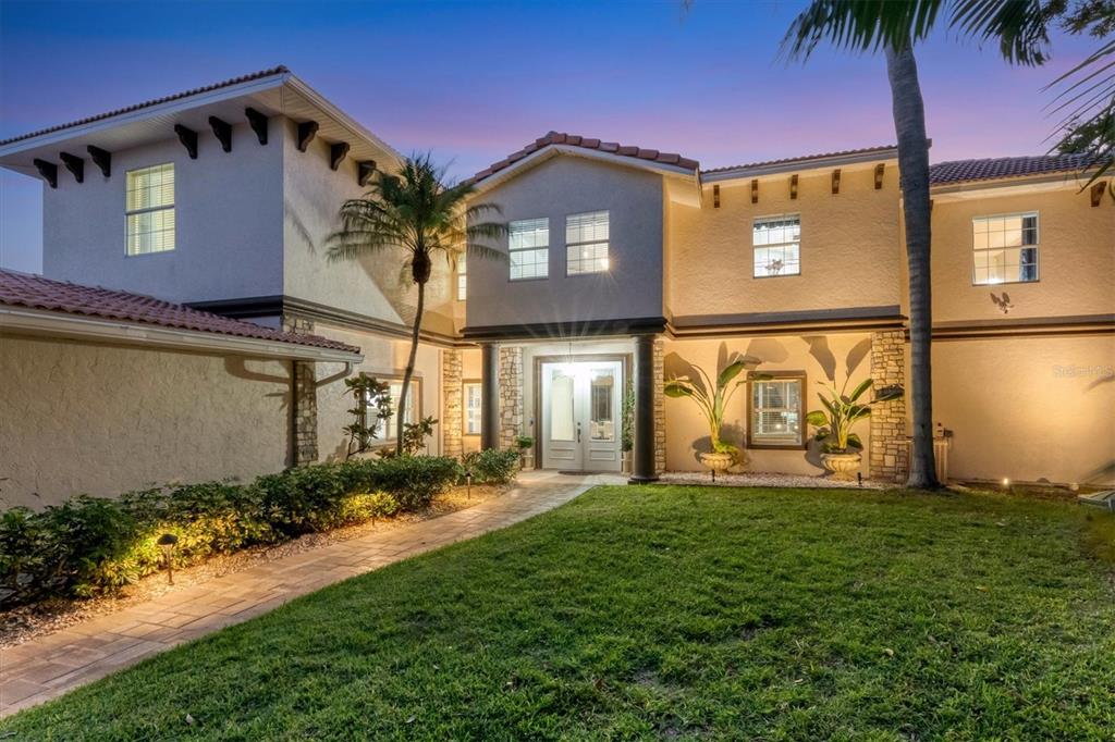 A two-story stucco house features a tiled roof, a stone-accented entrance, and a paved walkway — 7300 COVE TERRACE, SARASOTA, FL