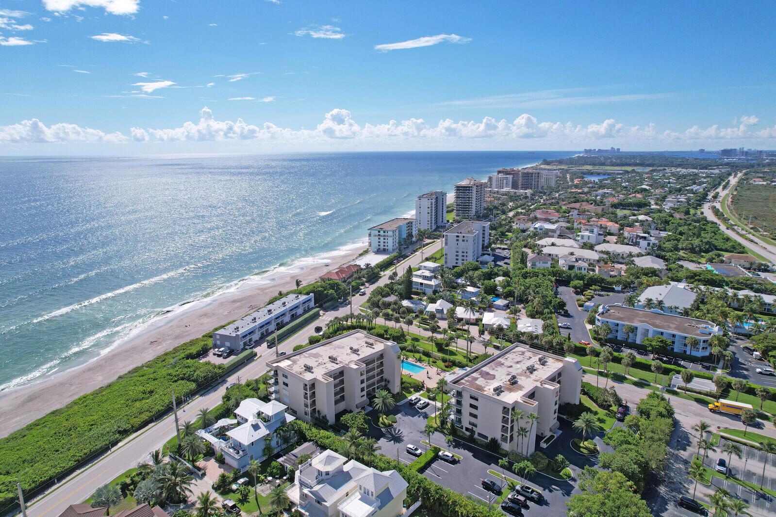 Aerial view of a coastal neighborhood with multi-story apartment buildings along a sandy beach — 1055 Ocean Drive # 403, Juno Beach FL 33408, JUNO BEACH, FL