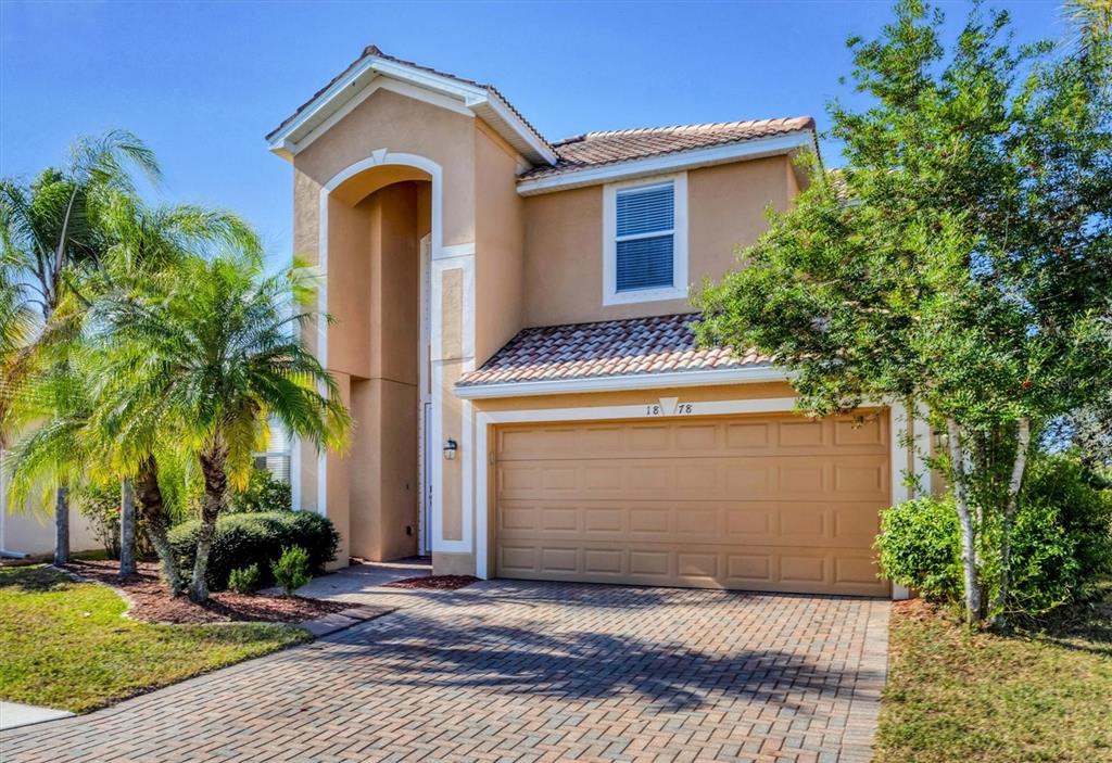 A two-story tan house with a tiled roof, a two-car garage, and palm trees — 1878 MESIC HAMMOCK WAY, VENICE, FL