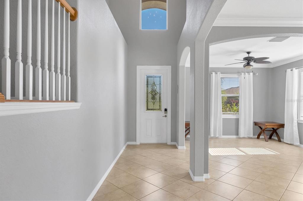 A bright entryway features tile flooring, a white front door, and a staircase with railings — 1878 MESIC HAMMOCK WAY, VENICE, FL