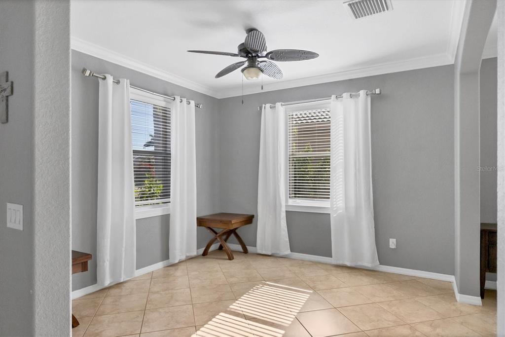 A room with gray walls, tile flooring, two windows with white curtains, and a ceiling fan — 1878 MESIC HAMMOCK WAY, VENICE, FL