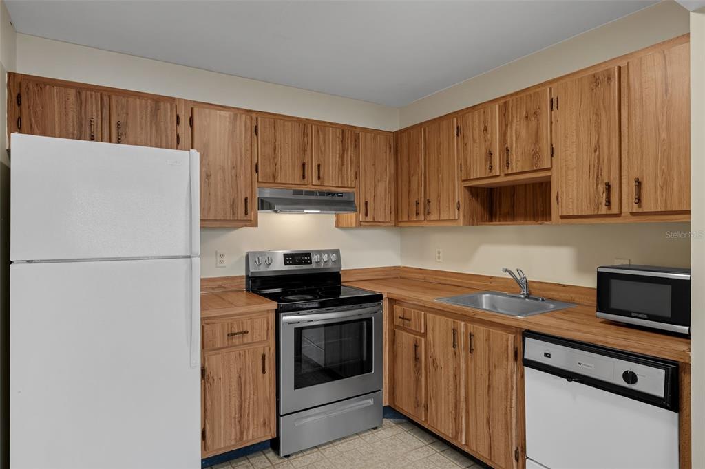 A kitchen with wood cabinets, laminate countertops, and stainless steel appliances — 2597 OAK PARK WAY UNIT 205, ORLANDO, FL