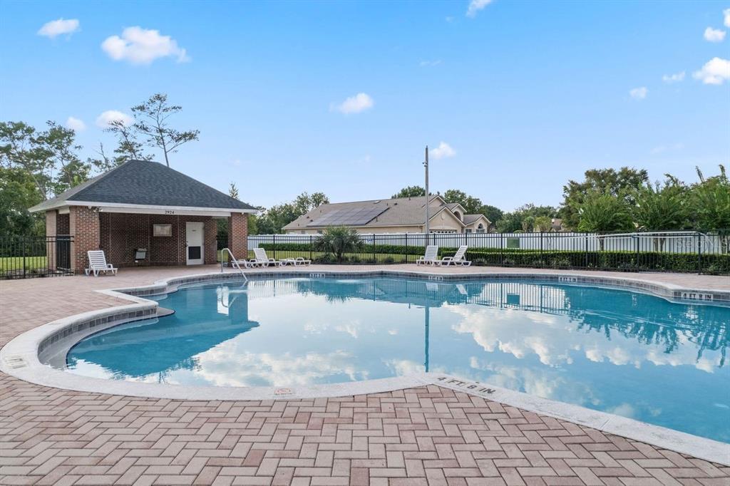 A swimming pool with a brick-paved deck and a covered pavilion under a blue sky — 3042 WILD PEPPER AVENUE, DELTONA, FL