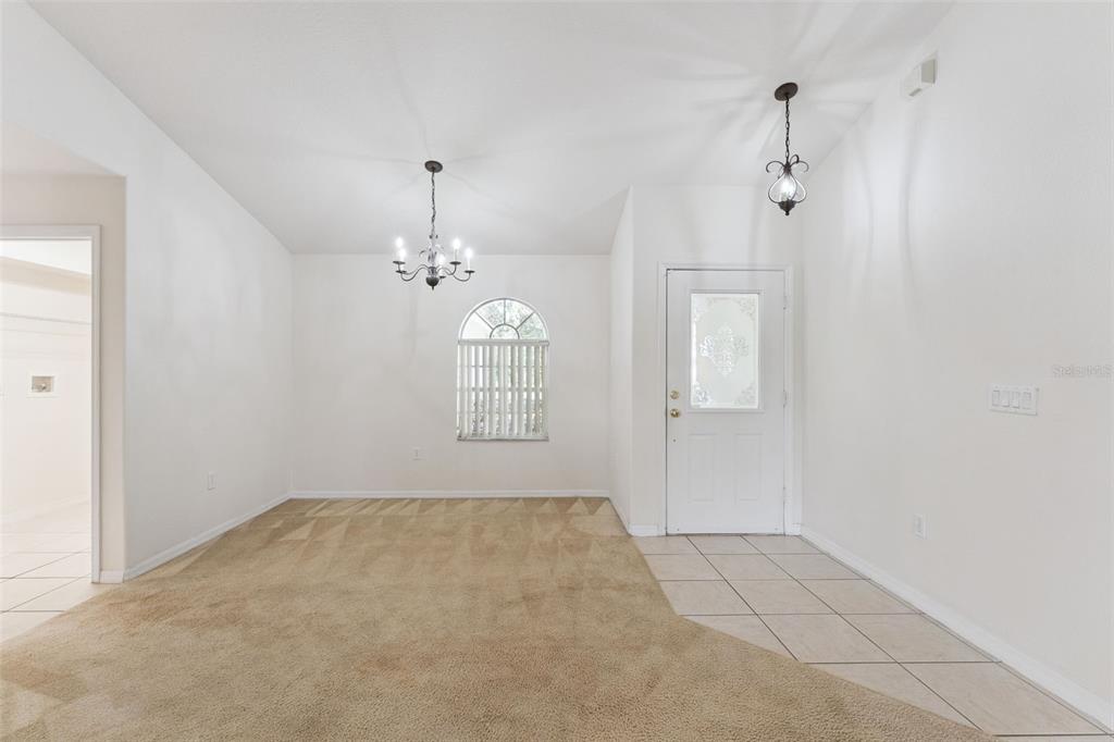 A room with beige carpet, a white front door, and two hanging light fixtures — 3042 WILD PEPPER AVENUE, DELTONA, FL