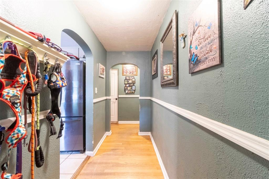 A hallway with teal walls, white wainscoting, and hardwood floors leads toward an arched doorway — 27 VOLUSIA DRIVE, DEBARY, FL