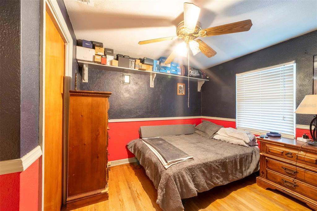 A bedroom with dark blue and red walls, a ceiling fan, and a wooden dresser — 27 VOLUSIA DRIVE, DEBARY, FL