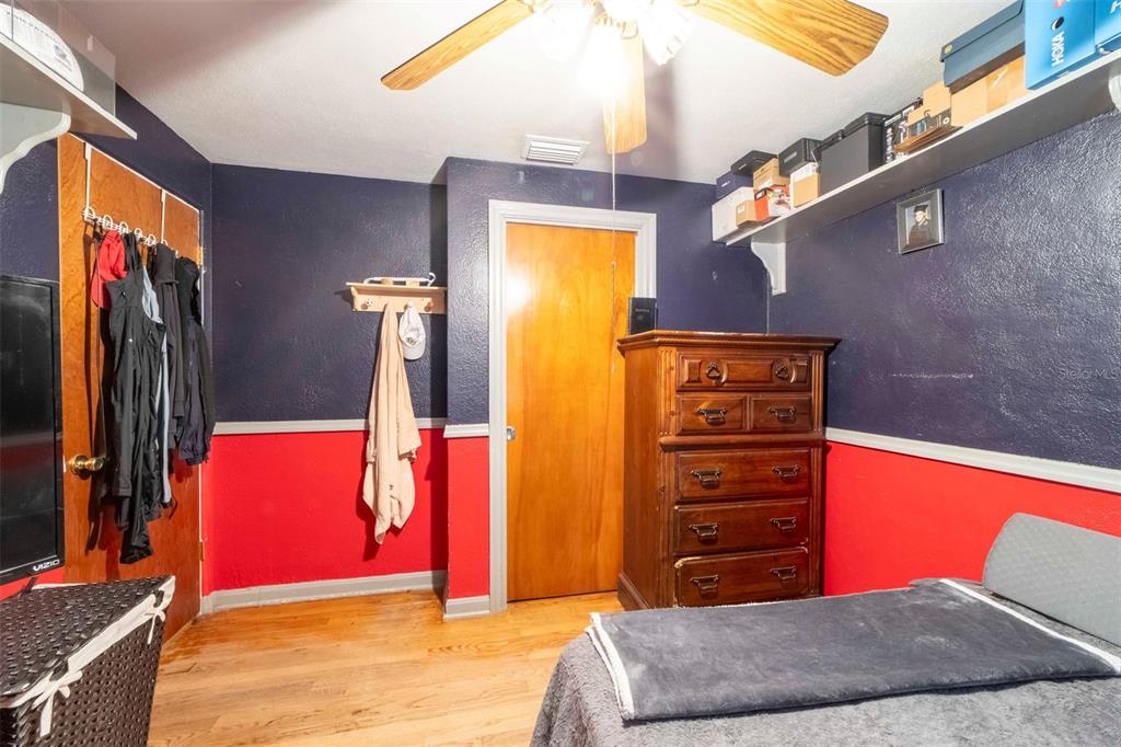 A bedroom features dark blue and red walls, a wooden dresser, and a ceiling fan — 27 VOLUSIA DRIVE, DEBARY, FL
