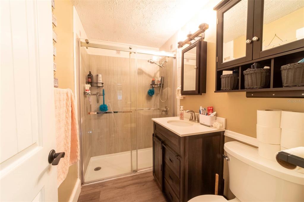 A bathroom features a glass-enclosed shower, a dark wood vanity, and a toilet — 27 VOLUSIA DRIVE, DEBARY, FL