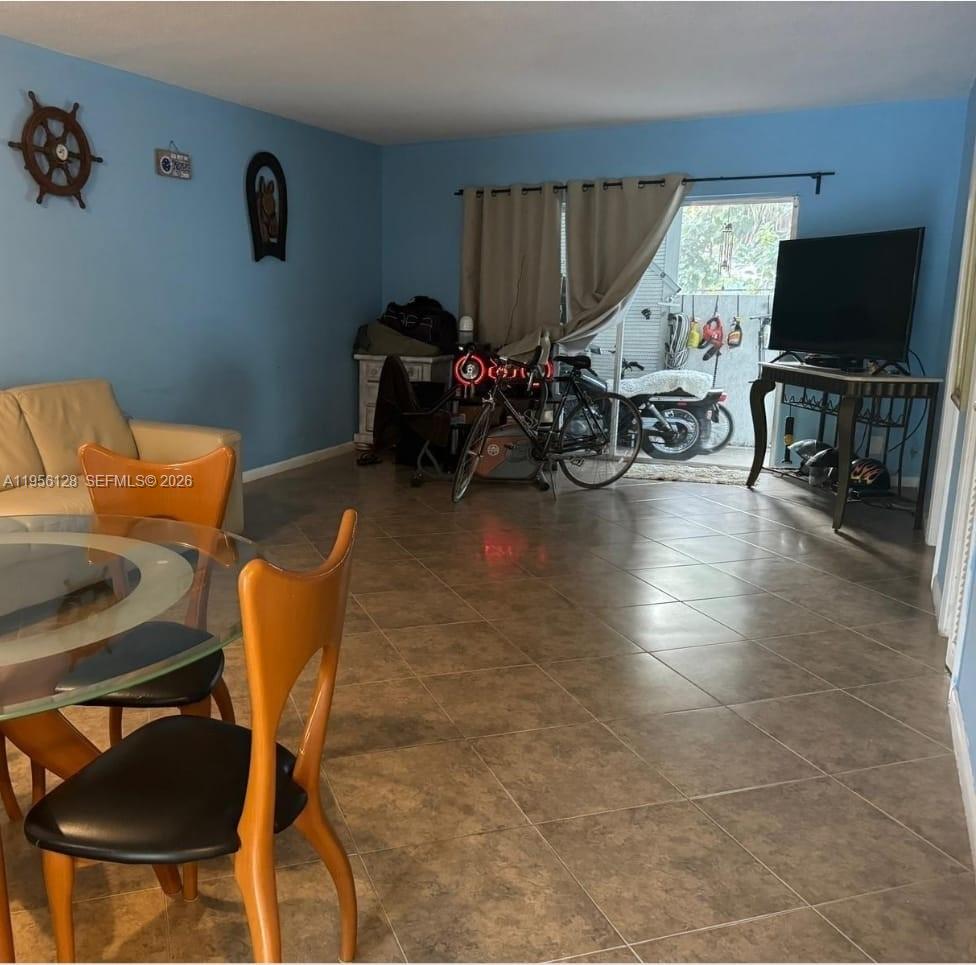 A living room with light blue walls, tile flooring, a dining set, and a bicycle — 4321 NW 9th Ave # 104, Deerfield Beach FL 33064, DEERFIELD BEACH, FL