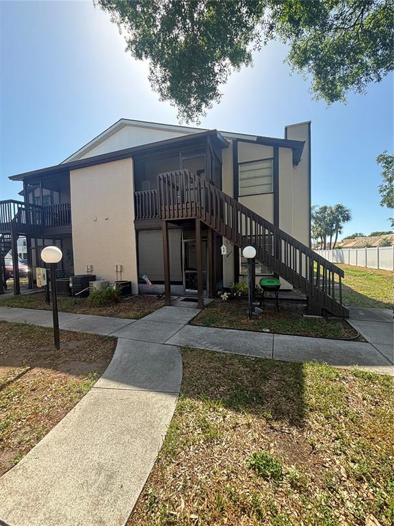 A two-story apartment building features a wooden staircase leading to an upper-level screened balcony — 3866 59TH AVENUE W UNIT 3866, BRADENTON, FL