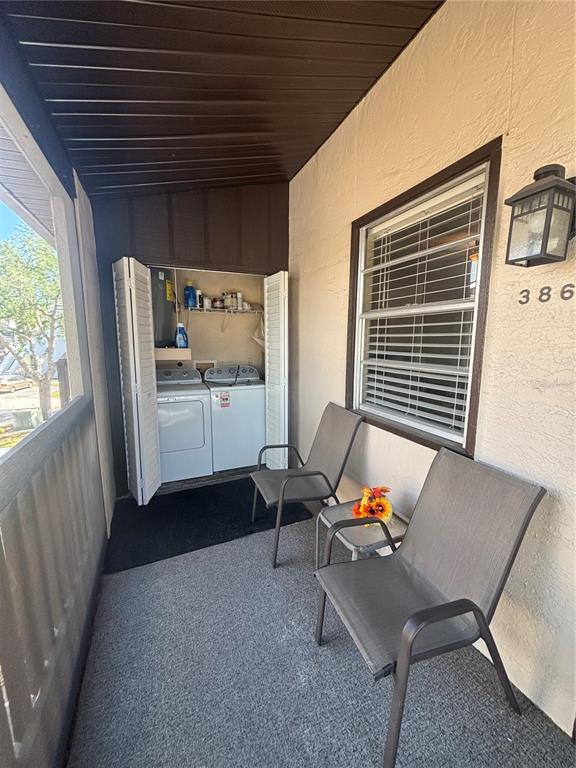 A covered balcony features two chairs, a small table, and a laundry closet with appliances — 3866 59TH AVENUE W UNIT 3866, BRADENTON, FL
