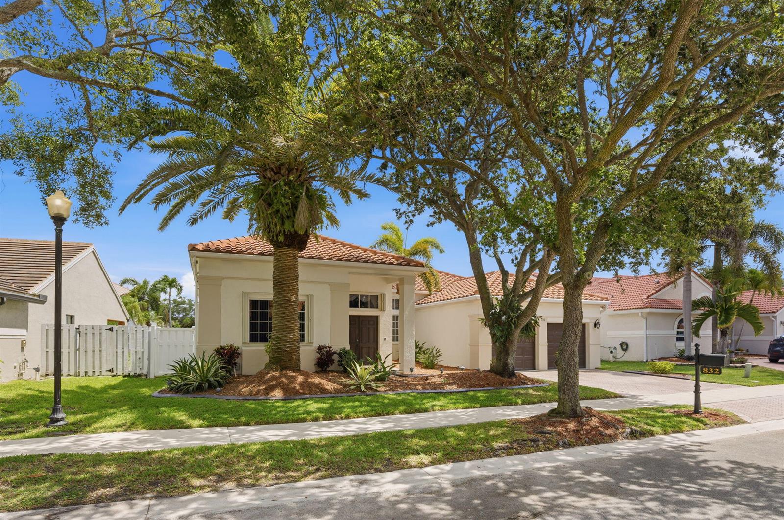 A single-story house with a tile roof, palm tree, and driveway under a clear sky — 832 Heritage Drive, Weston FL 33326, WESTON, FL