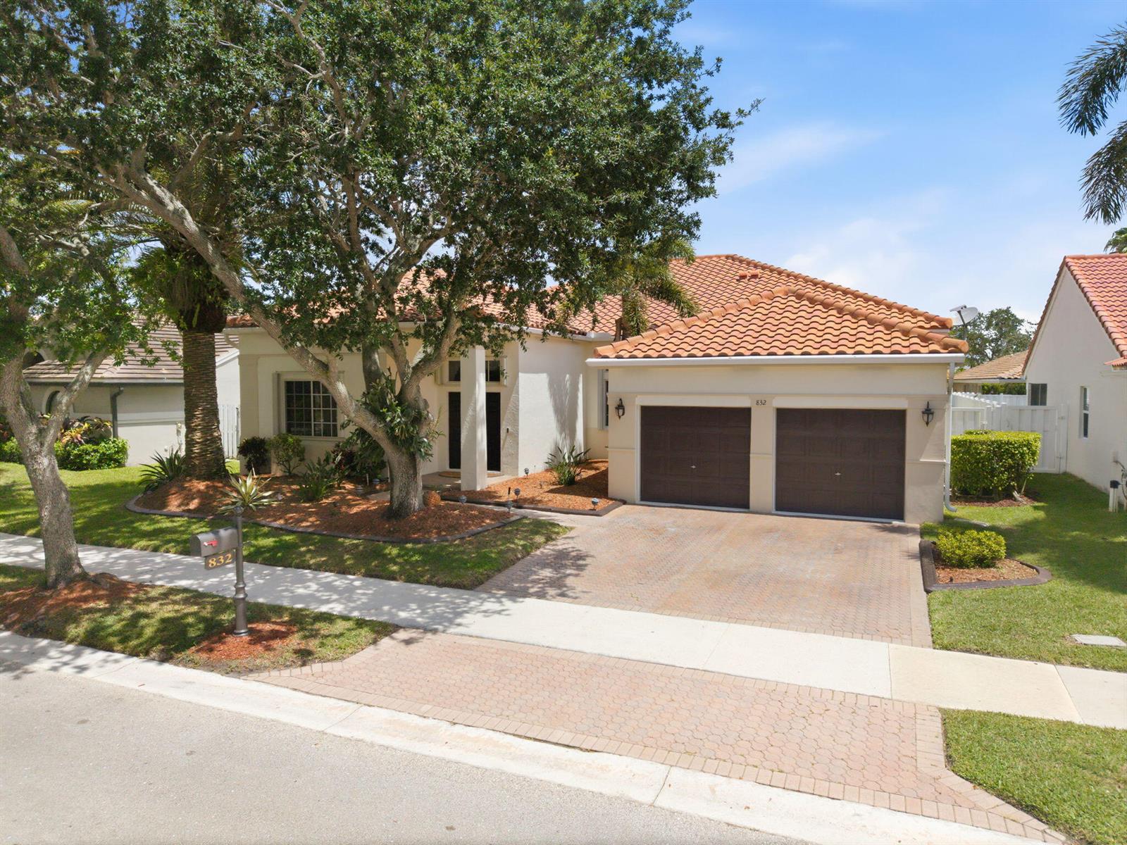 A single-story house with a tiled roof, two-car garage, and a large tree in front — 832 Heritage Drive, Weston FL 33326, WESTON, FL