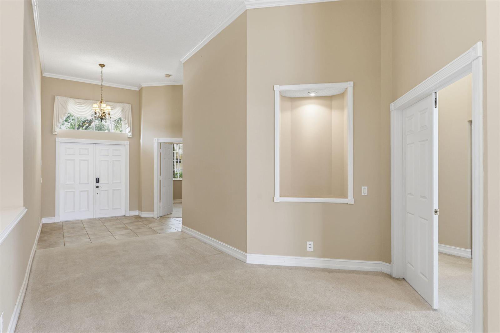 A carpeted foyer with a recessed wall niche, a chandelier, and double front doors — 832 Heritage Drive, Weston FL 33326, WESTON, FL