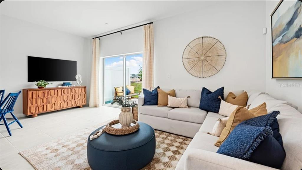 A living room features a sectional sofa, a round ottoman, and a wooden media console — 10798 ECLIPSE STREET, SARASOTA, FL