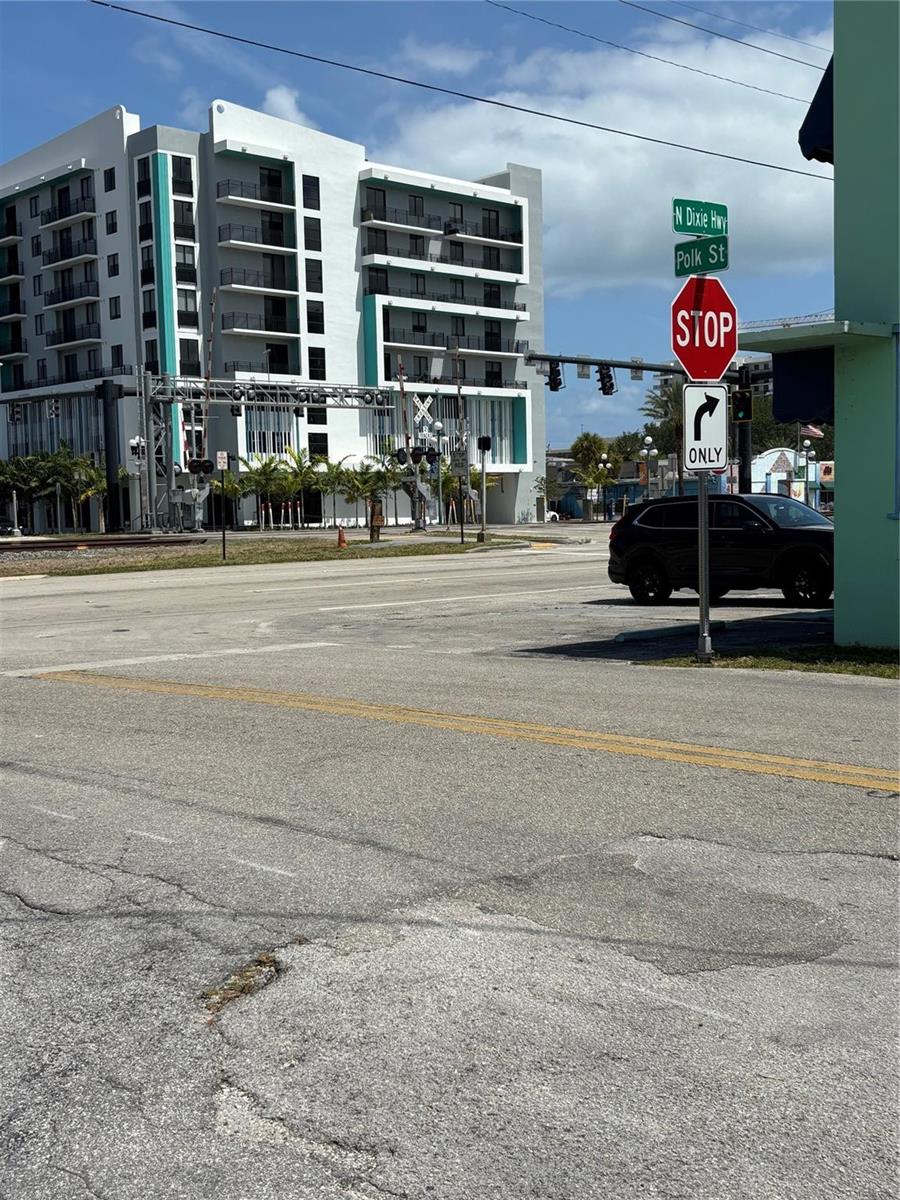 A street corner view shows a modern apartment building, railroad tracks, and a stop sign — 2117 Polk Street, Hollywood FL 33020, HOLLYWOOD, FL