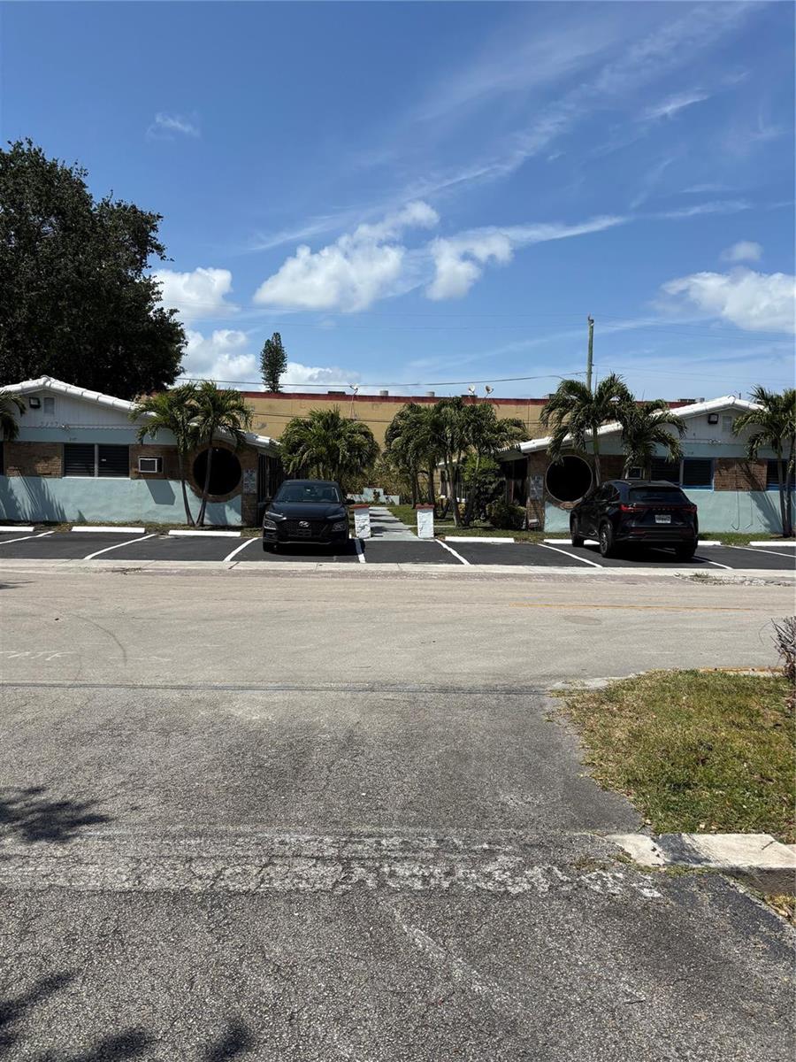 A low-rise apartment building with two parked cars in front under a blue sky — 2117 Polk Street, Hollywood FL 33020, HOLLYWOOD, FL