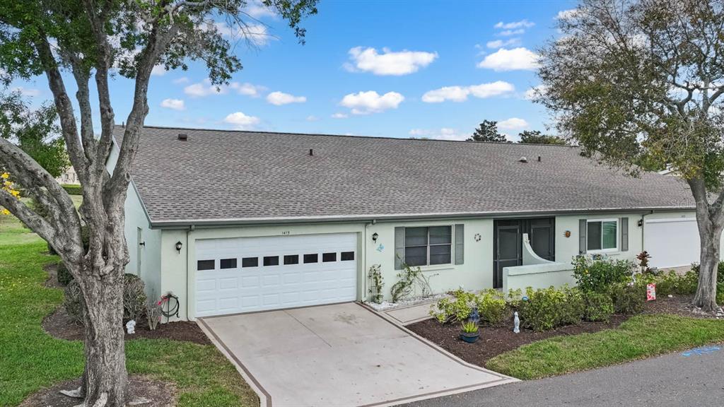 An exterior view of a light green single-story house with a white garage door — 1415 LANGLEY DRIVE, SUN CITY CENTER, FL