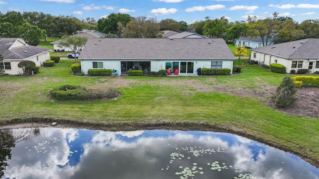 An aerial view shows the back of a house with a pond in the foreground — 1415 LANGLEY DRIVE, SUN CITY CENTER, FL