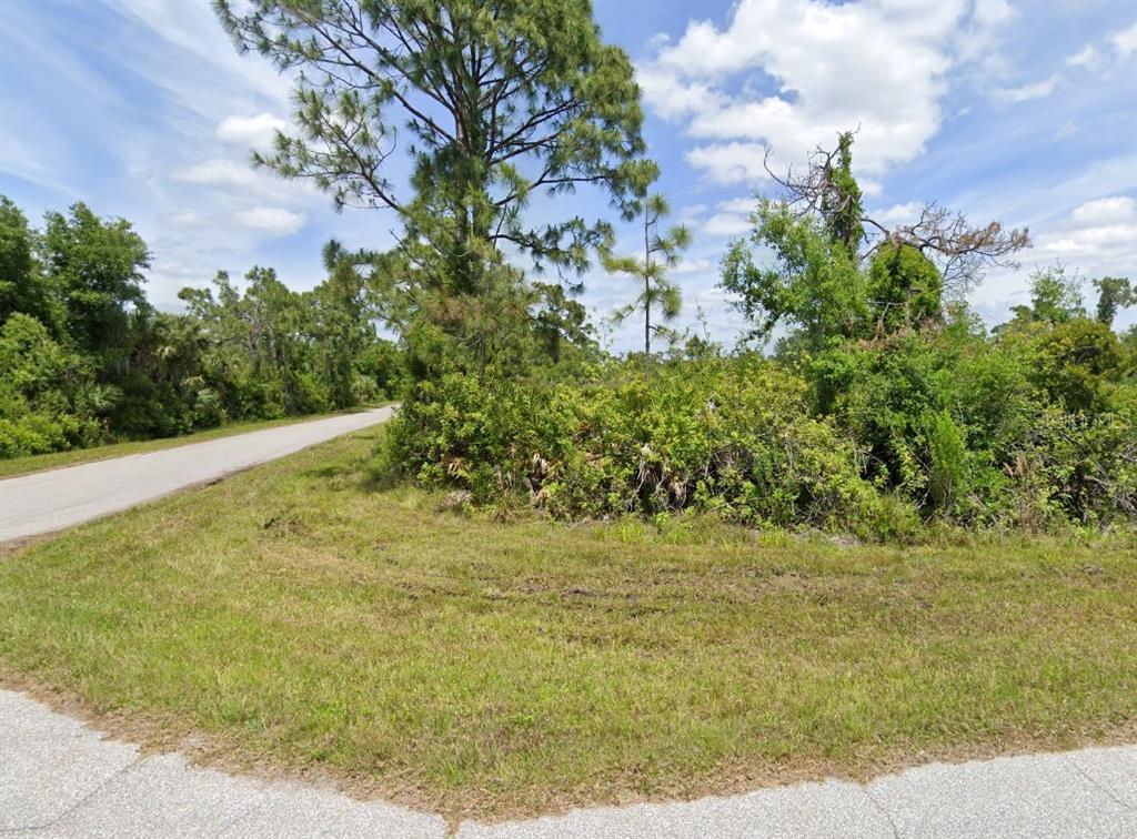 A vacant, wooded corner lot with grass and trees along a paved residential street — 3519 & 3527 DWIGHT STREET, PORT CHARLOTTE, FL