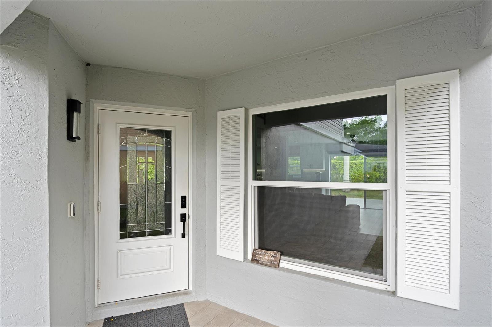 A white front door with a glass insert sits beside a window with white shutters — 133 SW 159th Way, Sunrise FL 33326, SUNRISE, FL
