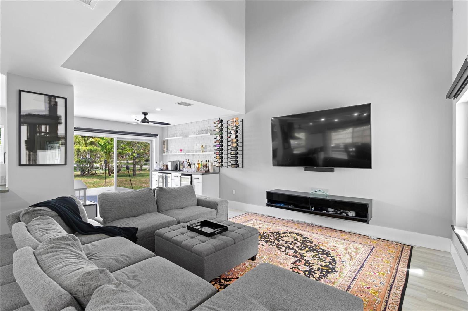 A living room features a grey sectional, a patterned rug, a wall-mounted TV, and a bar — 133 SW 159th Way, Sunrise FL 33326, SUNRISE, FL