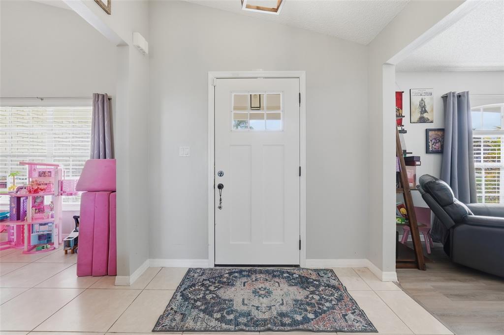 An entryway features a white front door, tiled flooring, and a patterned area rug — 14715 GREATER PINES BOULEVARD, CLERMONT, FL