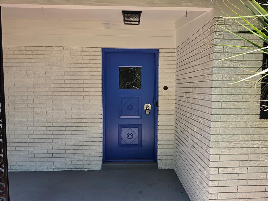 A bright blue front door is set into a white painted brick exterior wall — 640 WESTWARD CIRCLE, DAYTONA BEACH, FL