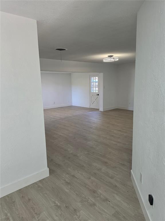 An interior view shows a white-walled room with light wood-look flooring and a glass-paneled door — 640 WESTWARD CIRCLE, DAYTONA BEACH, FL