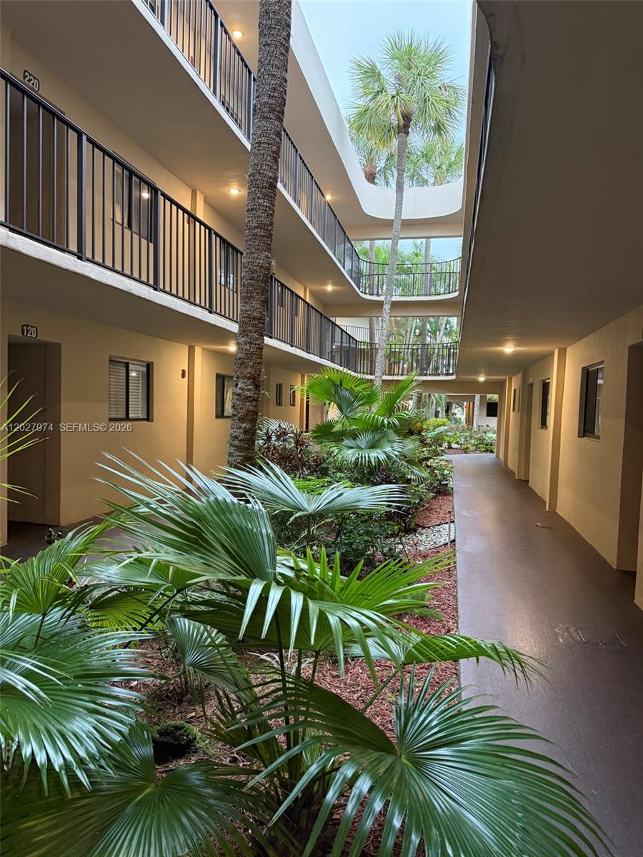 An open-air courtyard with palm trees is surrounded by multi-story apartment building walkways — 5220 Las Verdes Cir # 114, Delray Beach FL 33484, DELRAY BEACH, FL