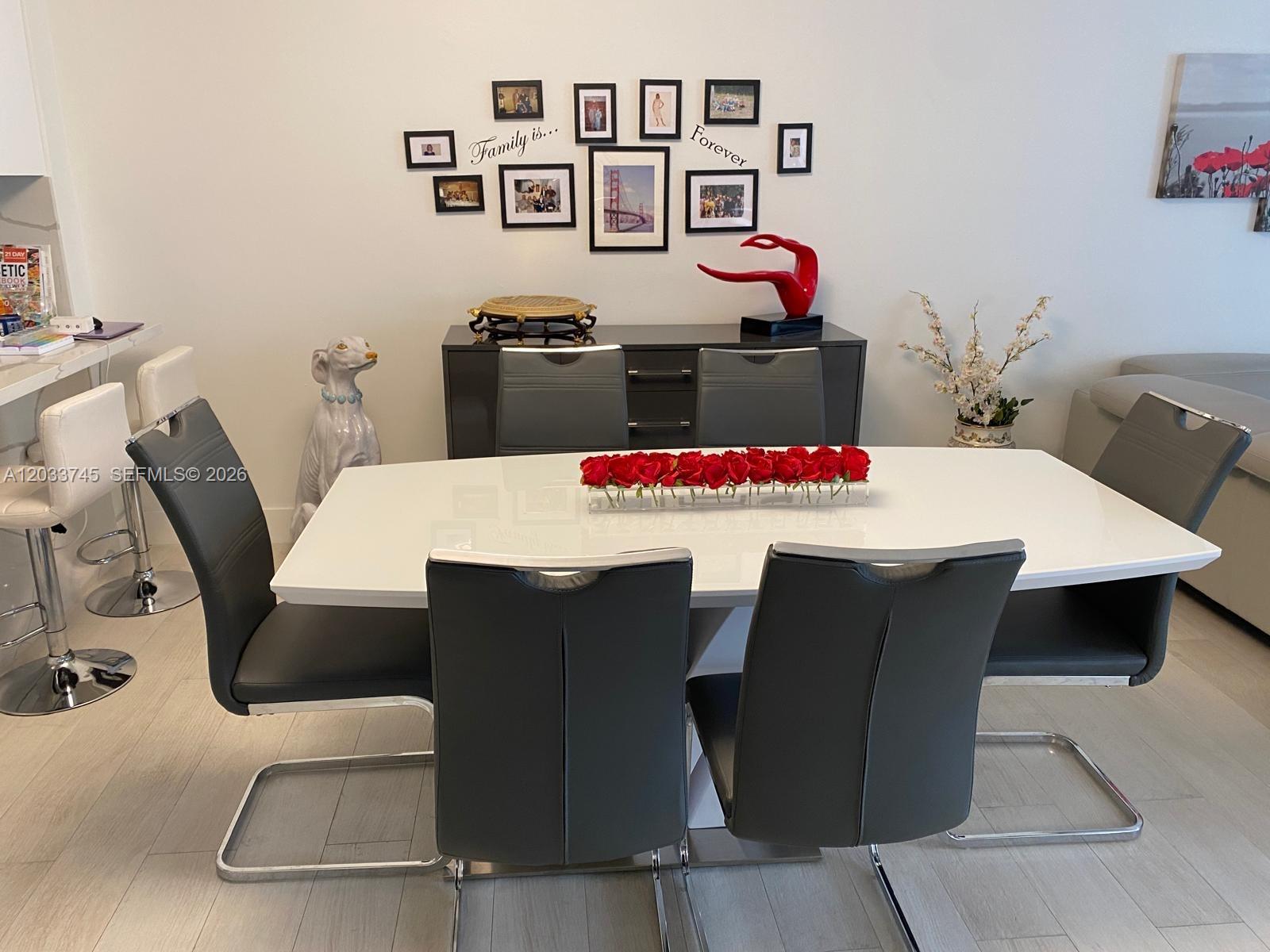 A dining room features a white table, grey chairs, a sideboard, and a photo gallery wall — 5601 Collins Ave # 622, Miami Beach FL 33140, MIAMI BEACH, FL