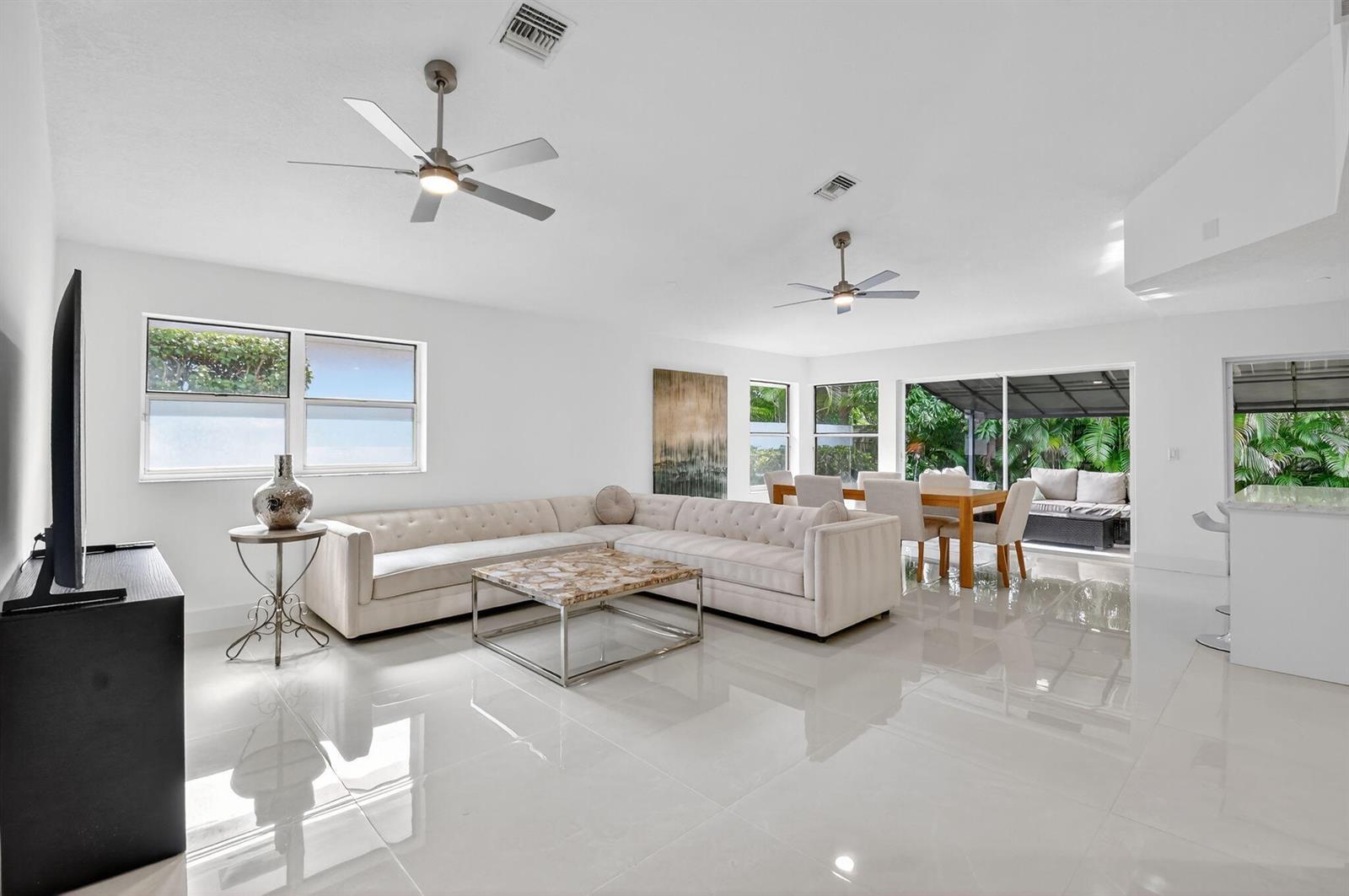 A bright living and dining area with white tile floors, two ceiling fans, and furniture — 2218 NW 52nd Street, Boca Raton FL 33496, BOCA RATON, FL