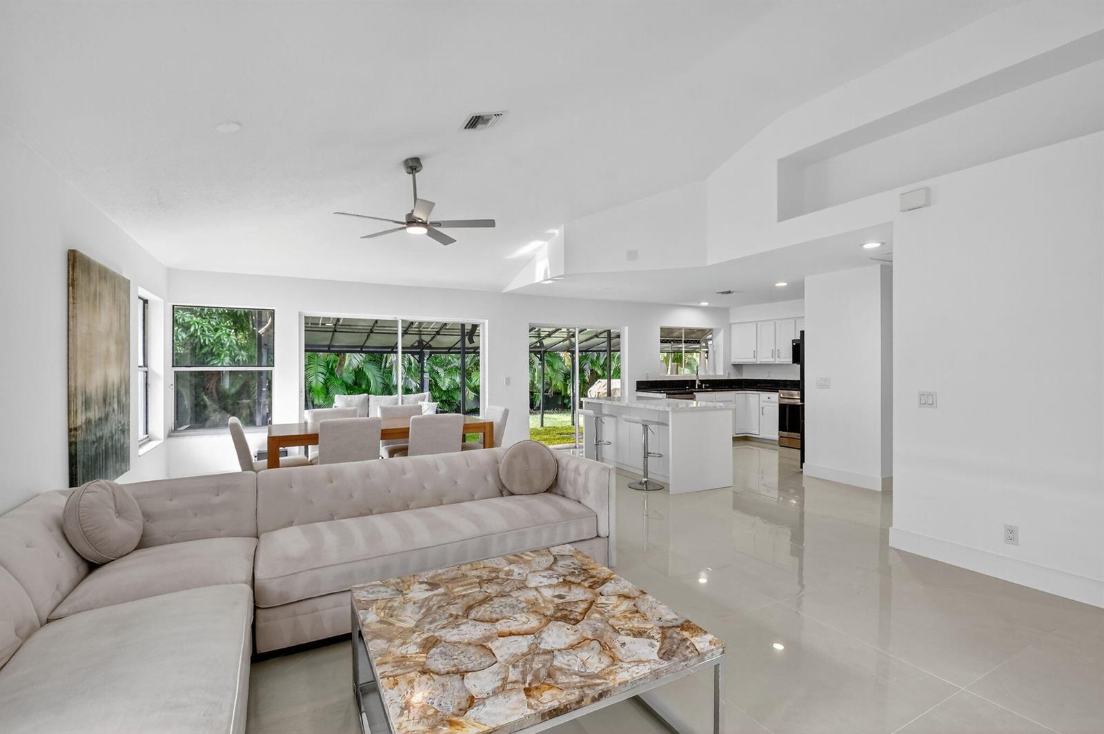A bright open-concept living room and kitchen feature white walls, tile floors, and sliding doors — 2218 NW 52nd Street, Boca Raton FL 33496, BOCA RATON, FL