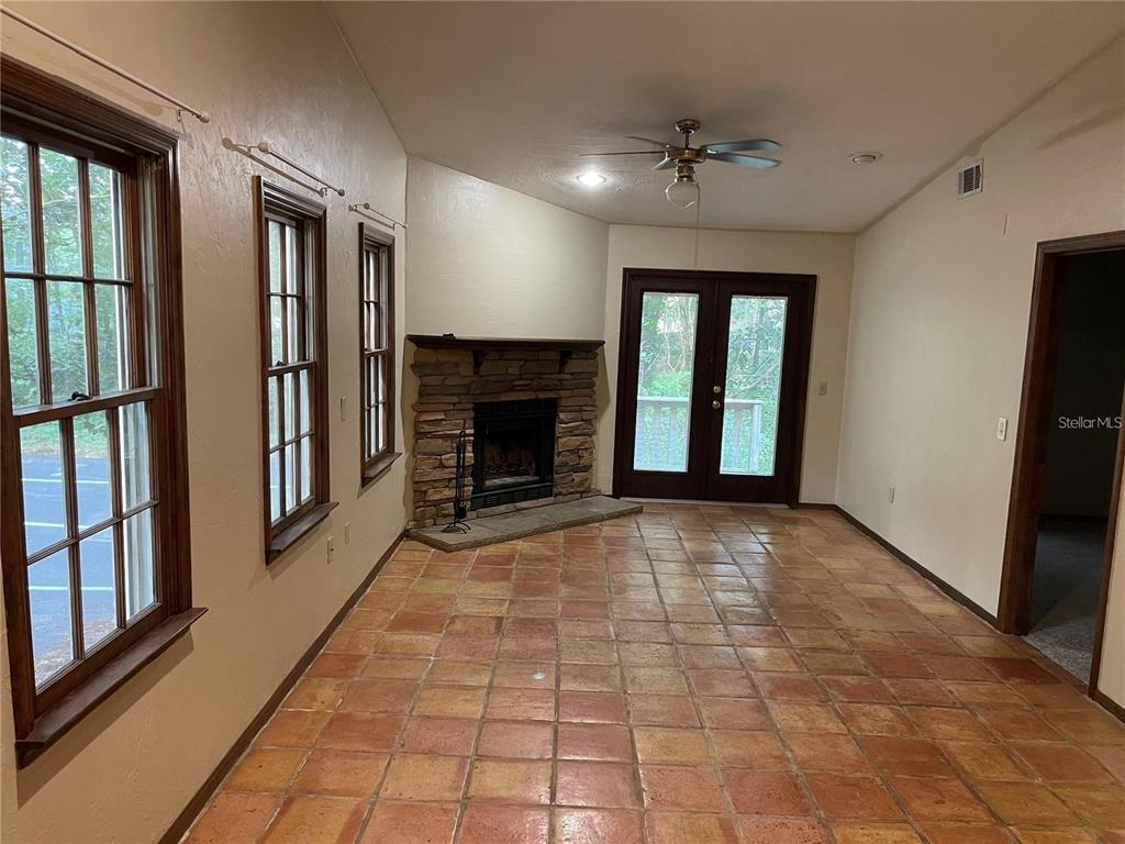 A living room features a stone corner fireplace, tile flooring, and glass French doors — 5213 SW 92ND COURT, GAINESVILLE, FL