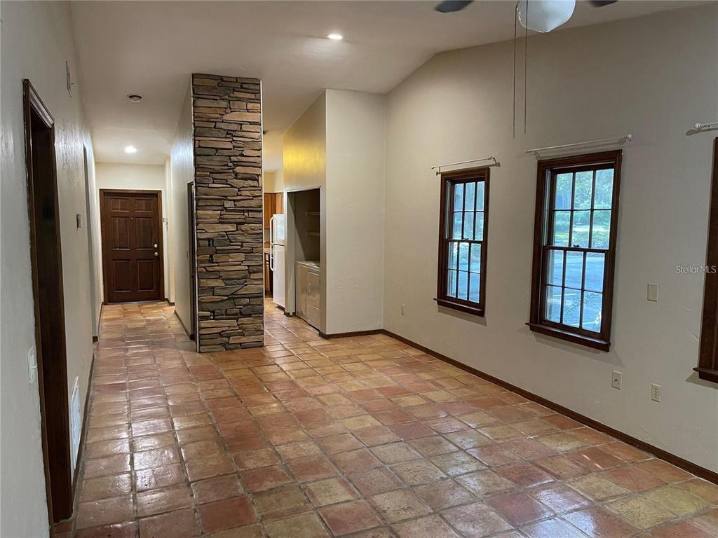 A room with terracotta tile flooring, a stone-faced pillar, and two windows on the wall — 5213 SW 92ND COURT, GAINESVILLE, FL