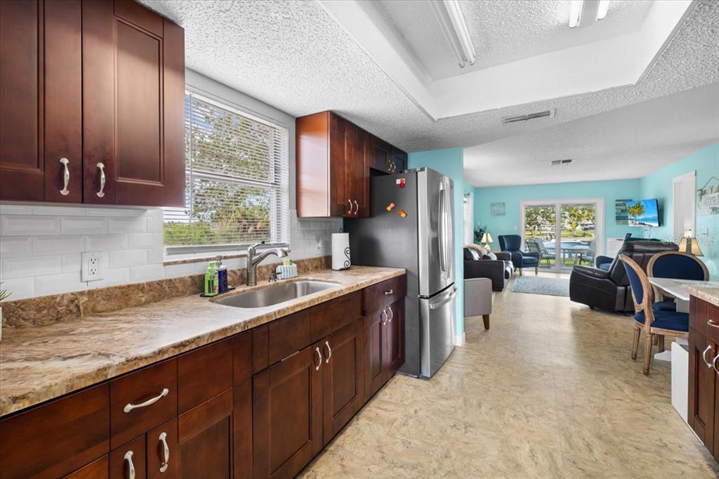 A kitchen with dark wood cabinets, granite countertops, and a stainless steel refrigerator — 3478 COMPANERO ENTRA, HERNANDO BEACH, FL