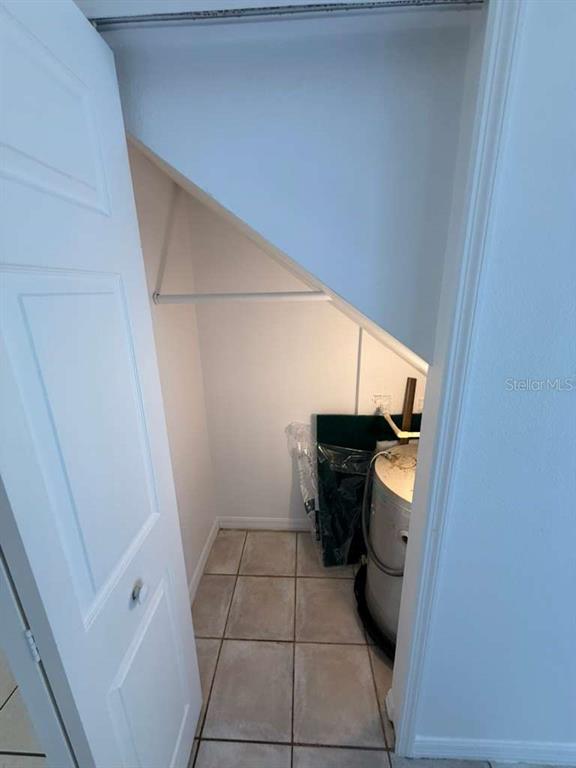 A small closet with tiled flooring contains a water heater and a sloped ceiling — 4478 SAINT GEORGES COURT UNIT A, KISSIMMEE, FL