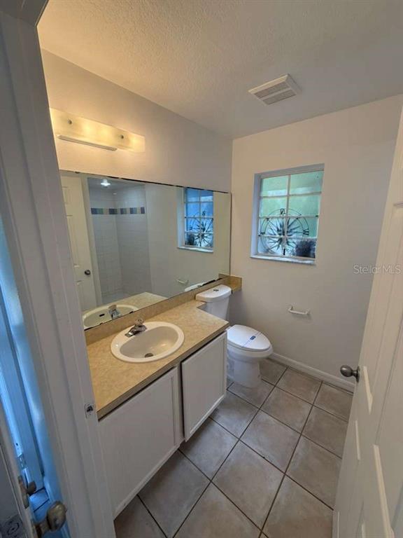 A bathroom features a vanity with a sink, a toilet, and a large wall mirror — 4478 SAINT GEORGES COURT UNIT A, KISSIMMEE, FL