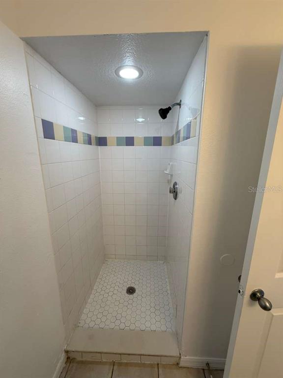 A walk-in shower with white subway tile walls, a decorative blue border, and hexagonal floor tiles — 4478 SAINT GEORGES COURT UNIT A, KISSIMMEE, FL