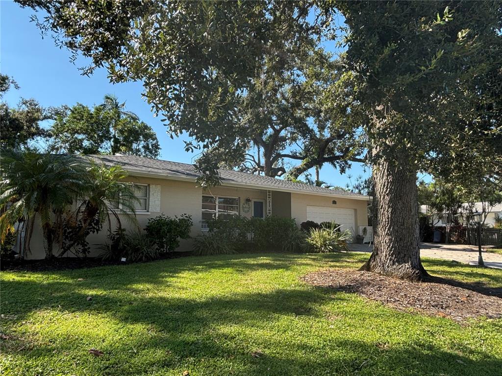 A single-story house with a beige exterior, a garage, and large trees in the front yard — 1214 21ST STREET W, BRADENTON, FL