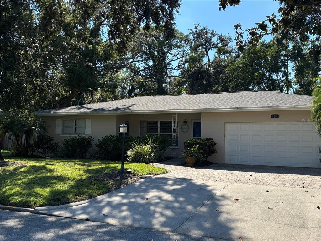A single-story house with a beige exterior, a paved driveway, and a two-car garage — 1214 21ST STREET W, BRADENTON, FL