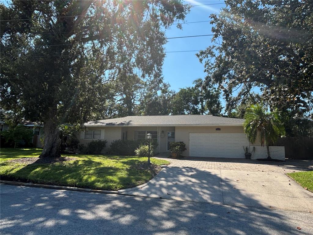 A single-story house with a beige exterior, a two-car garage, and a large front yard — 1214 21ST STREET W, BRADENTON, FL